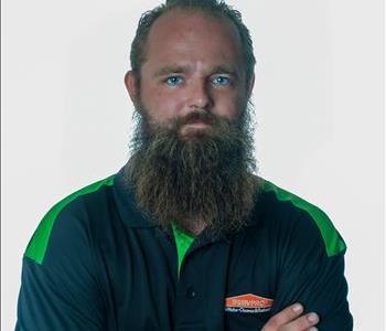 Man with a beard in SERVPRO uniform posing for a picture on a white background