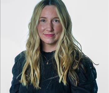 Blonde woman in SERVPRO uniform posing for a picture on a white background