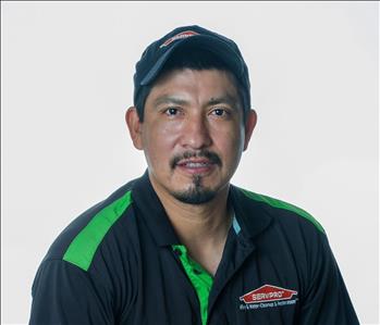 Man in a hat and SERVPRO uniform posing for a picture on a white background