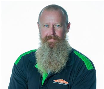 Man with a beard in SERVPRO uniform posing for a picture on a white background