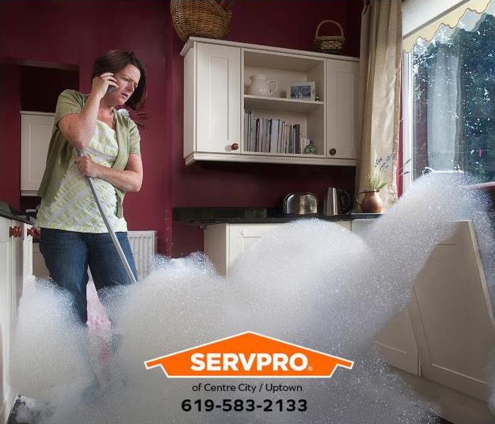 A woman calls for emergency help while watching her dishwasher overflow. 