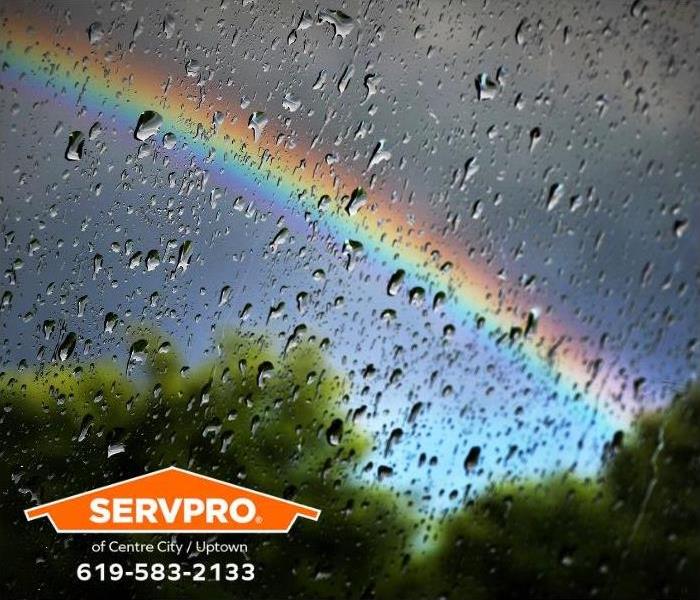 A rainbow can be seen out of a window on a rainy day.