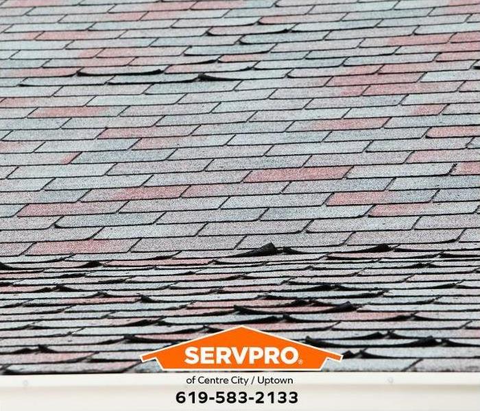 An asphalt roof shows visible signs of storm damage.