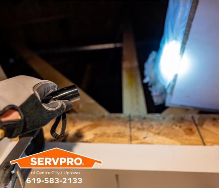 A person inspects the attic space for signs of loose or damaged insulation after a windstorm.