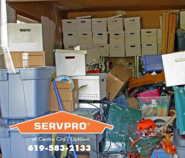 A room is shown filled with boxes, storage bins, and plastic bags.